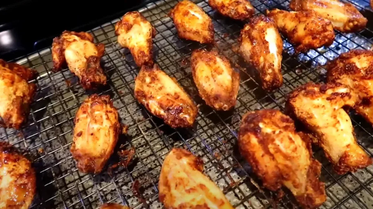 Crispy air fryer wings coated in a flavorful glaze, served hot with dipping sauce and garnished with fresh herbs.