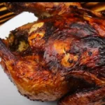 A golden-brown air fryer whole chicken on a serving platter, fresh out of the air fryer