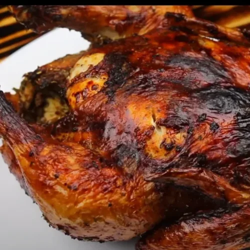 A golden-brown air fryer whole chicken on a serving platter, fresh out of the air fryer