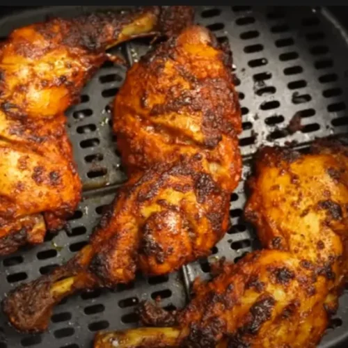 Plated air fryer chicken thighs garnished with fresh parsley, served with roasted vegetables