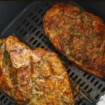 A perfectly cooked air fryer chicken breast, sliced and fanned out, served with a fresh green salad.
