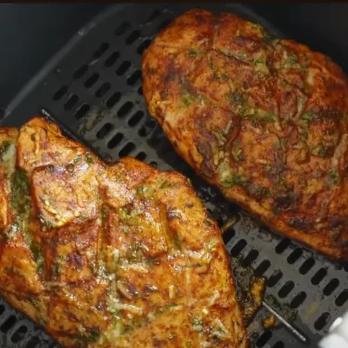 A perfectly cooked air fryer chicken breast, sliced and fanned out, served with a fresh green salad.