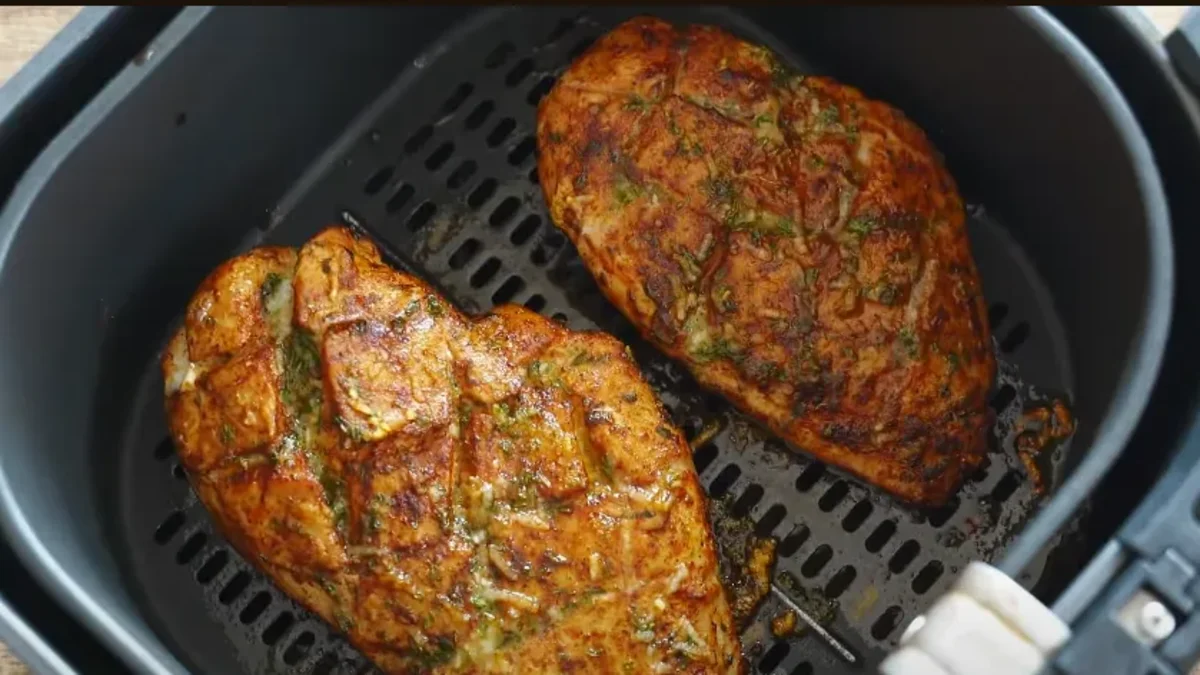 A perfectly cooked air fryer chicken breast, sliced and fanned out, served with a fresh green salad.