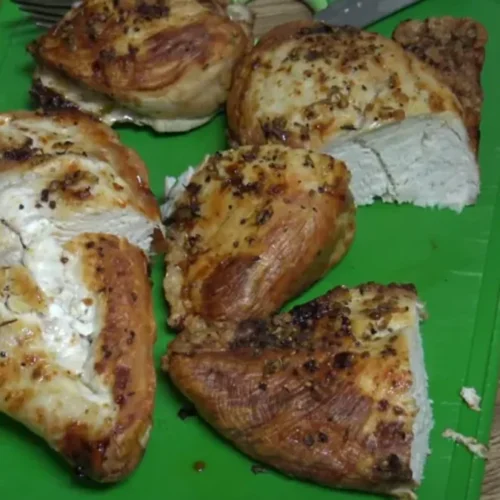 frozen chicken breast air fryer being placed in an air fryer basket.